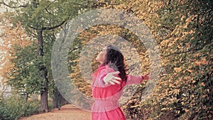 Happy woman in a red cloak walking in autumn park, concept of freedom