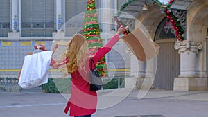 Happy woman in a red coat with shopping bags.