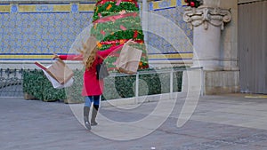 Happy woman in a red coat with shopping bags.