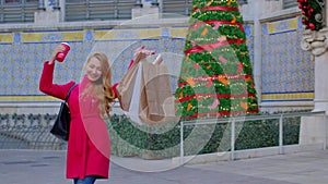 Happy woman in a red coat with shopping bags and a coffee.