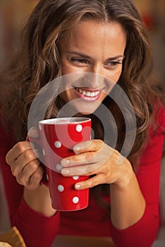 Happy woman in red dress having cup of hot beverage