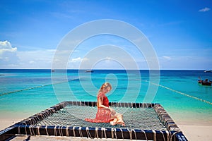 Happy woman in red dress relaxing hammock tropical beach