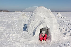 Happy woman in a red jacket lying in an igloo