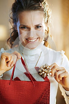 Happy woman with red shopping bag taking out purchased sweater