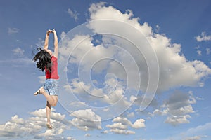 Happy woman on red T-shirt jumping to blue clound sky photo