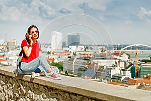 Žena v červenom hovorí o chytrý telefón na pozadí moderného európskeho mesta