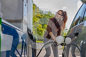 Happy woman refueling car looking at the machine