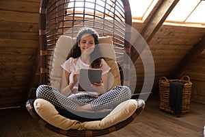 Happy woman relax in chair at home using tablet