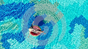 Happy woman relaxes on a rubber ring in a pool.