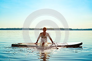 Happy woman relaxes on SUP board and enjoy life
