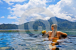 Happy woman relaxing in Batur volcano hot spring spa