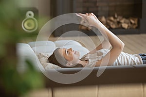 Happy woman relaxing on cozy couch using cellphone