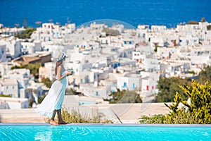 Happy woman relaxing on the edge of pool with amazing view on Mykonos, Greece