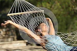 Happy woman relaxing on a hammock on holidays and raising arms