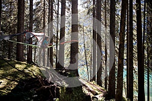 Happy woman relaxing in hanging tent camping in lake forest woods during sunny day.Group of friends people summer