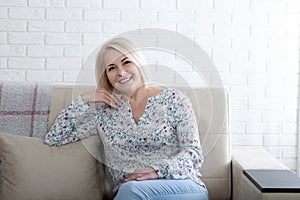 Happy woman relaxing on her couch at home in the sitting room. Age is just a number and I love every minute of it.