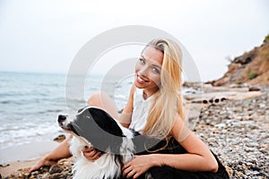 Happy woman relaxing with her dog on the beach