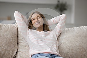 Happy woman relaxing leaned on cushions of comfortable couch