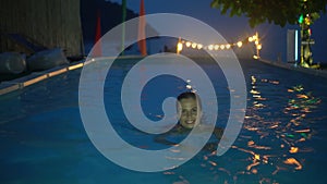 Happy woman relaxing at the luxury swimming pool in the evening. 4k video of woman at the swimming pool