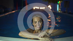 Happy woman relaxing at the luxury swimming pool in the evening. 4k video of woman at the swimming pool