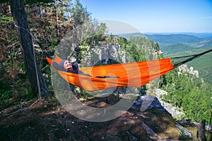 Happy woman relaxing lying in hammock on top of mountain. Summer travel lifestyle.