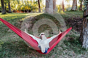 Happy woman relaxing in orange hammock. Camping outdoors. autumn season at sunset