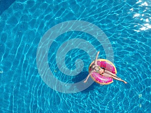 Happy woman relaxing with in pool with donut mattress