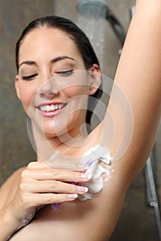 Happy woman removing armpit hair in the shower