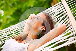 Happy woman, rest and wellness on hammock in outdoor, peace and summer vacation in sunshine in nature. Young person