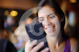 Happy woman in a restaurant using phone