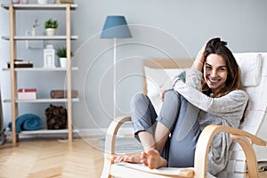 Happy woman resting comfortably sitting on modern chair in the living room at home