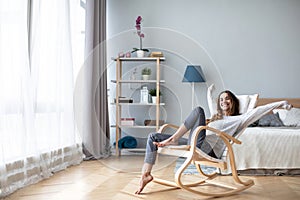 Happy woman resting comfortably sitting on modern chair in the living room at home