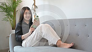 Happy woman resting on sofa and using mobile phone for ordering deliveryà¹ƒ