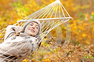 Happy woman rests on hammock looks at side in autumn
