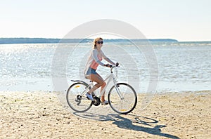 Happy woman riding bicycle along summer beach