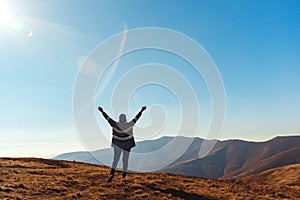 Happy woman rising hands up on top of autumn mountain. Beautiful view on autumn mountains. Travel, freedom and happiness,