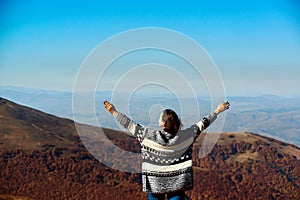 Happy woman rising hands up on top of autumn mountain. Travel, freedom and lifestyle