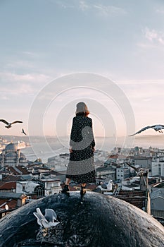 Happy woman on the roof with a view of Istanbul and seagulls in the sky, Turkey. A girl at dawn with a view of the city.