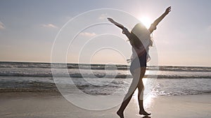 Happy woman running and spinning on the beach near the ocean. Young beautiful girl enjoying life and having fun at sea