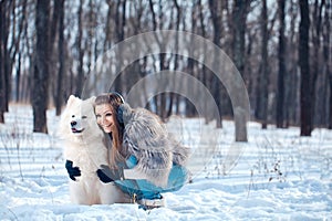 Happy woman with Samoyed dog in winter forest