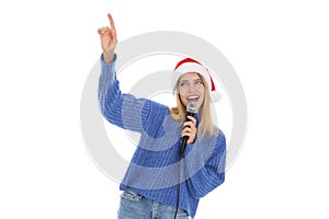 Happy woman in Santa Claus hat singing with microphone on white background. Christmas music