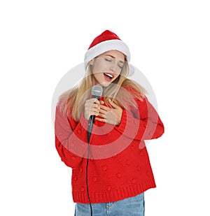 Happy woman in Santa Claus hat singing with microphone on white background. Christmas music