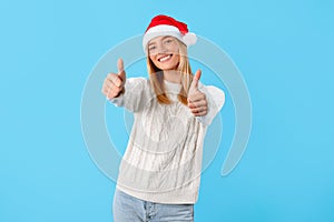 Happy woman in Santa hat giving thumbs up