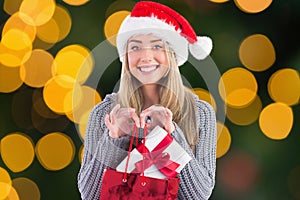 Happy woman in santa hat holding gift in shopping bag