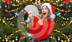 Happy woman in santa hat with money on christmas