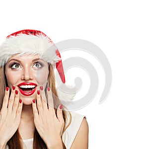 Happy woman in Santa hat with red manicure nails near red lips isolated. Surprised Christmas girl looking up