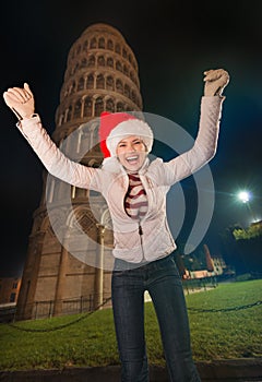 Happy woman in Santa hat rejoicing near Leaning Tower of Pisa