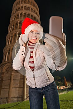 Happy woman in Santa hat taking selfie near Leaning Tower, Pisa