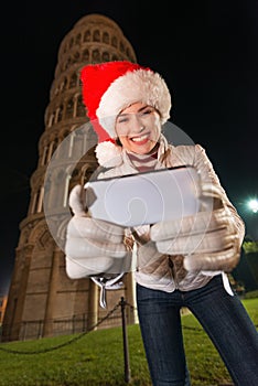 Happy woman in Santa hat writing sms near Leaning Tower, Pisa