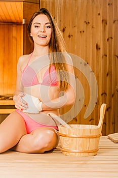 Happy woman in sauna with exfoliating glove.